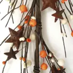 Orange and cream pip berry garland with rusty stars for primitive farmhouse, fall, Thanksgiving, and country home decorating.
